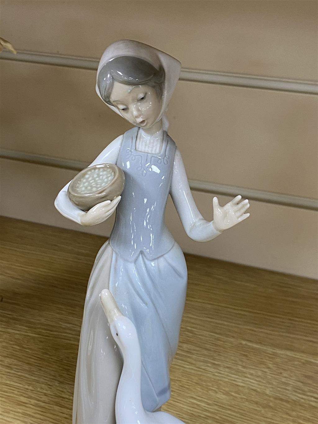 Three Lladro figures, two Nao figures.